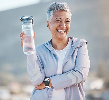 Woman smiling with water bottle on hike outside