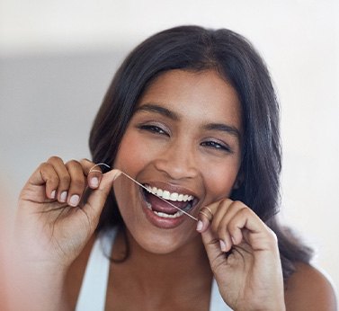 Woman smiling while flossing her teeth