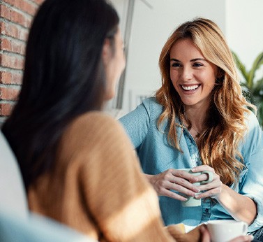 Woman smiling while drinking coffee with friend