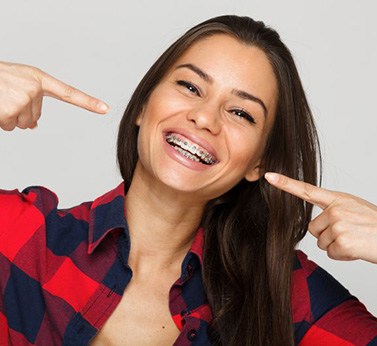 Happy young woman pointing at her braces