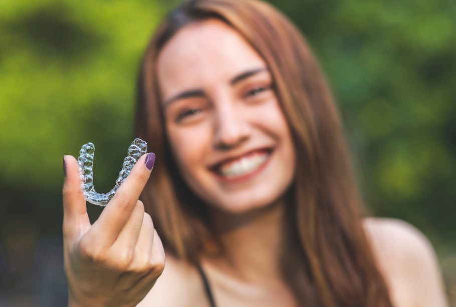 Woman holding up clear aligner